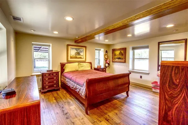 a spacious bedroom with a bed and wooden floor