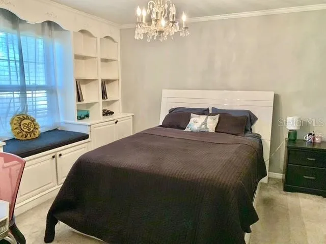 a bed sitting in a bedroom next to a window with a chandelier