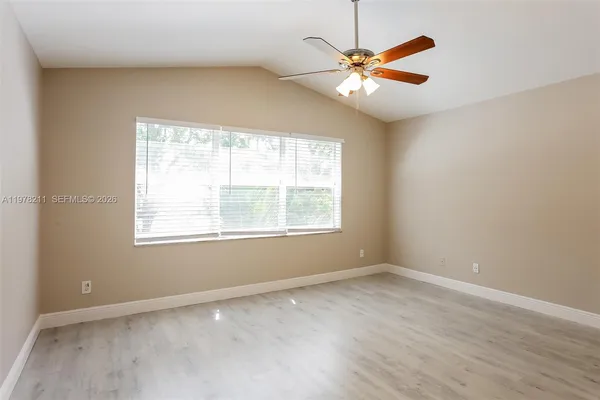 an empty room with window and ceiling fan