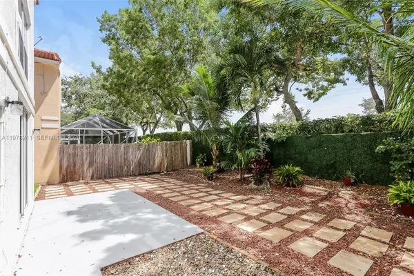 a view of a backyard with large trees and wooden fence
