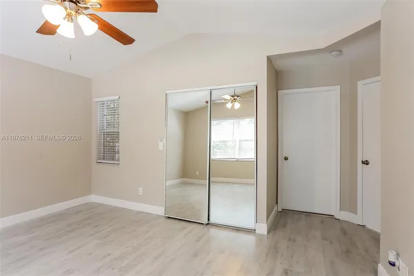 an empty room with wooden floor fan and windows