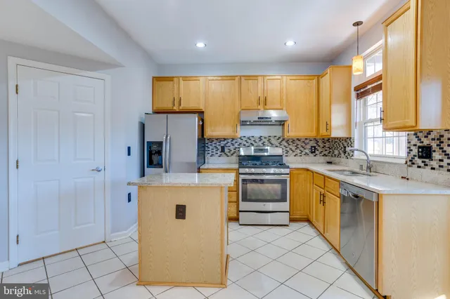 a kitchen with stainless steel appliances granite countertop a stove a sink and a refrigerator
