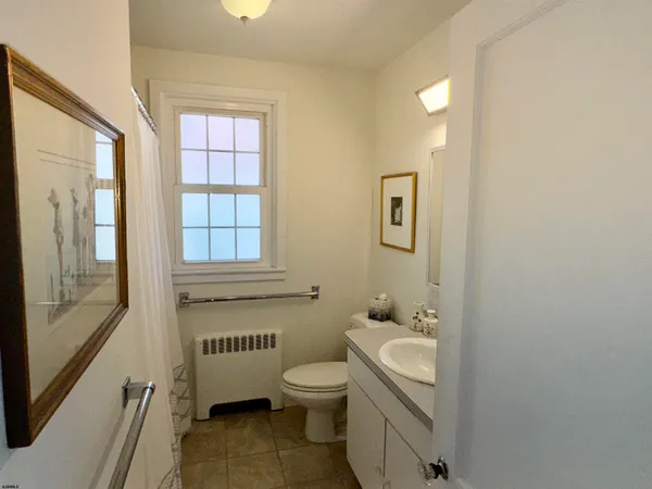a bathroom with a granite countertop toilet a sink and a window