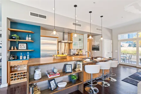 a room with stainless steel appliances a dining table chairs and a book shelf