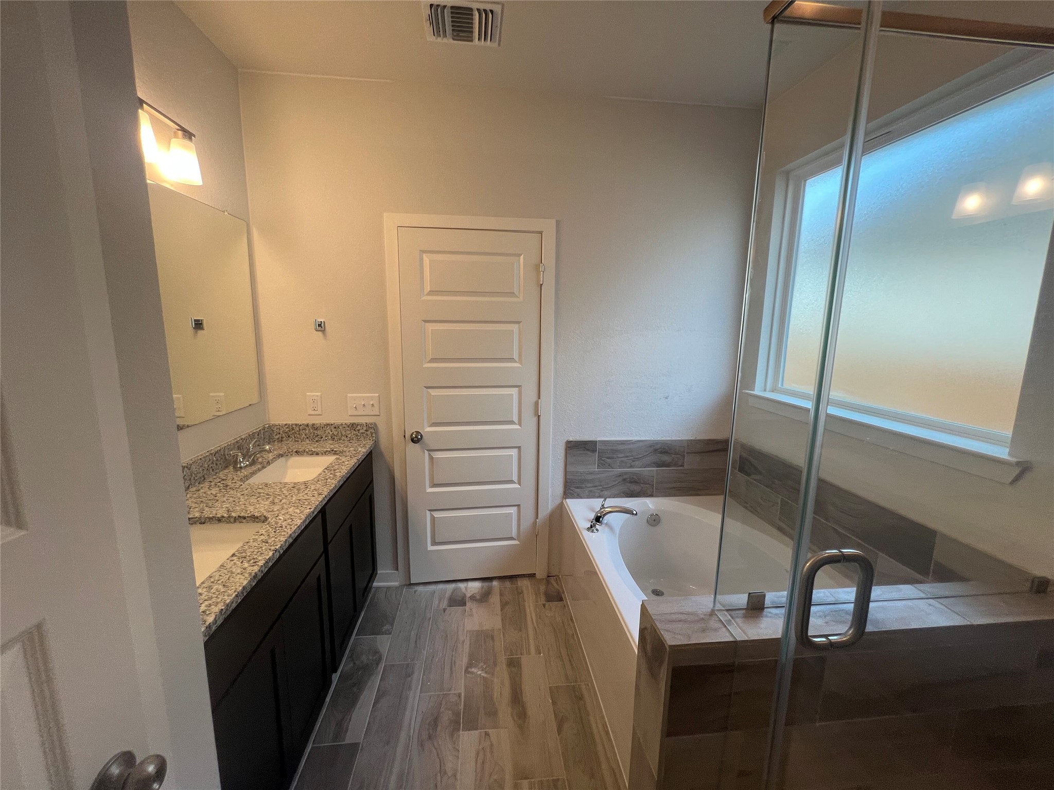 255 Gus Loop Georgetown, TX 78626 - Photo 20 of 24 Luxurious primary bathroom featuring a double vanity with stone counters, a separate soaking tub, and a glass-enclosed shower.