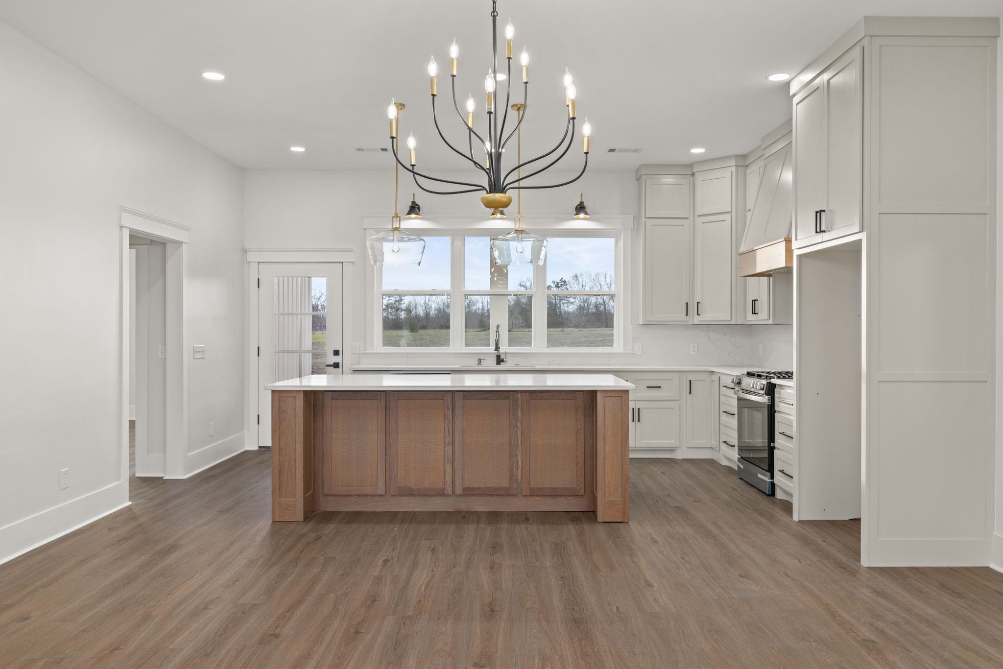 69 County Road 157 Corinth, MS 38834 - Photo 10 of 39 Kitchen featuring a chandelier, gas range, a center island, dark wood-style flooring, and two tone cabinets