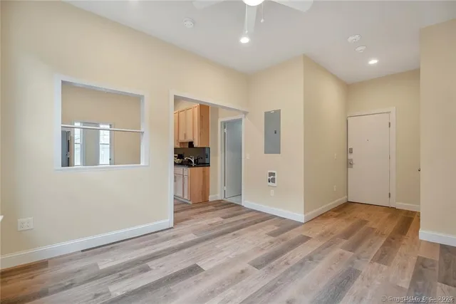 a view of an empty room with wooden floor and a kitchen