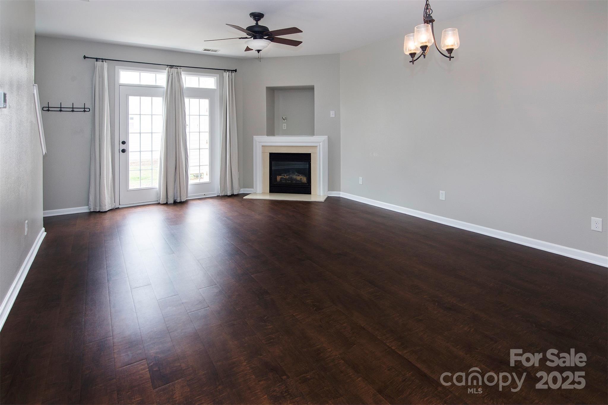 6310 Rhodins Lane Fort Mill, SC 29707 - Photo 12 of 22 an empty room with wooden floor fireplace and windows
