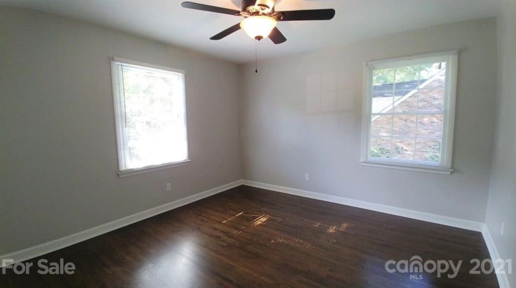 6517 Park Road Charlotte, NC 28210 - Photo 14 of 20 an empty room with wooden floor chandelier fan and windows