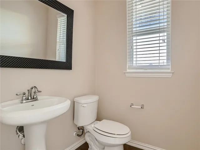 a bathroom with a toilet a sink a mirror and a window