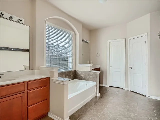 a spacious bathroom with a granite countertop tub sink and mirror
