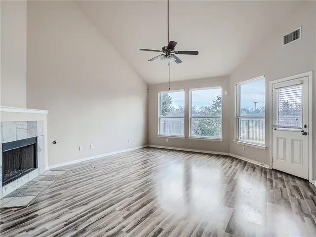 a view of an empty room with wooden floor fireplace and a window