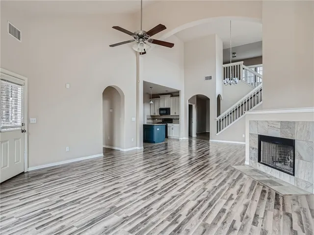 a view of a livingroom with a fireplace a ceiling fan and wooden floor
