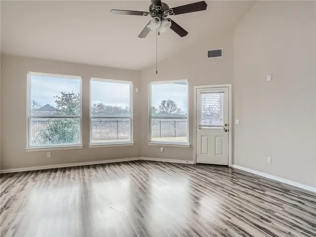 a view of empty room with wooden floor and fan