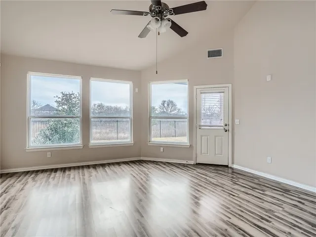 a view of empty room with wooden floor and fan