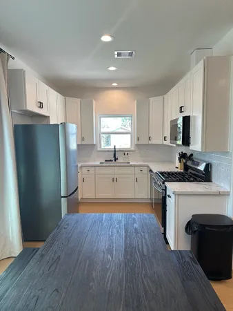 a kitchen with a refrigerator a stove top oven a sink and cabinets