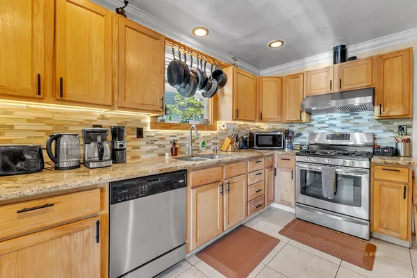 a kitchen with stainless steel appliances granite countertop a stove a sink and a microwave