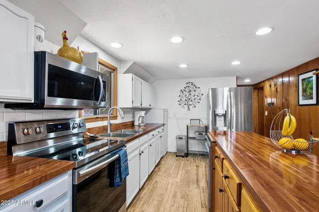 a kitchen with stainless steel appliances a stove a sink a microwave a refrigerator and cabinets