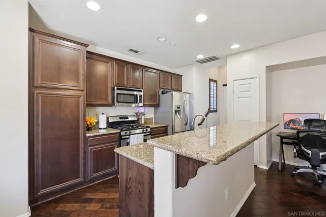 a kitchen with kitchen island granite countertop stainless steel appliances cabinets a sink and a refrigerator