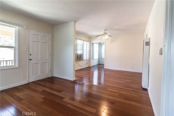 an empty room with wooden floor and windows