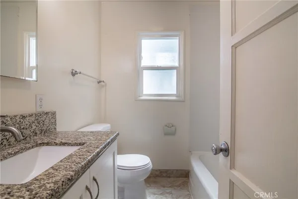 a bathroom with a granite countertop sink a toilet and shower