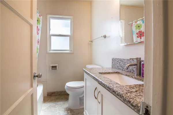 a bathroom with a granite countertop sink and a toilet