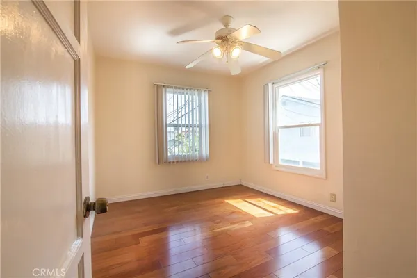 an empty room with wooden floor and windows