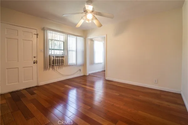 a view of an empty room with wooden floor and a window