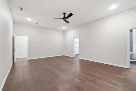 an empty room with wooden floor ceiling fan and windows