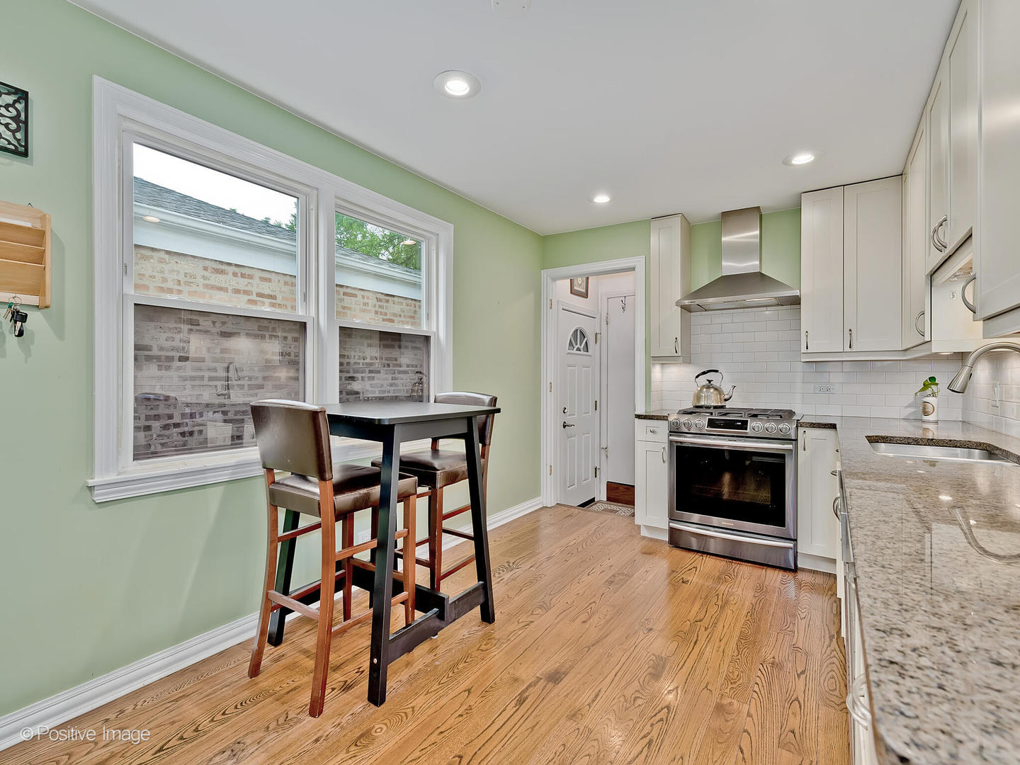 1910 Warren Street Evanston, IL 60202 - Photo 7 of 22 a kitchen with stainless steel appliances kitchen island granite countertop a stove a sink a refrigerator white cabinets and wooden floor