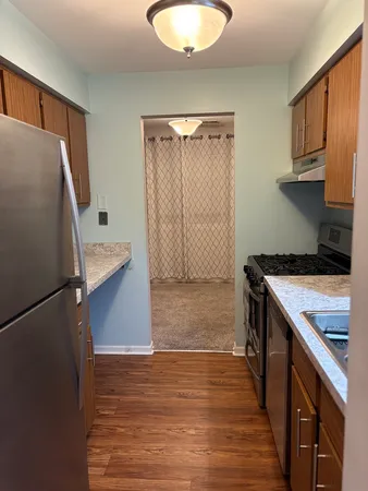 a kitchen with stainless steel appliances granite countertop a refrigerator a stove and a sink with wooden floors