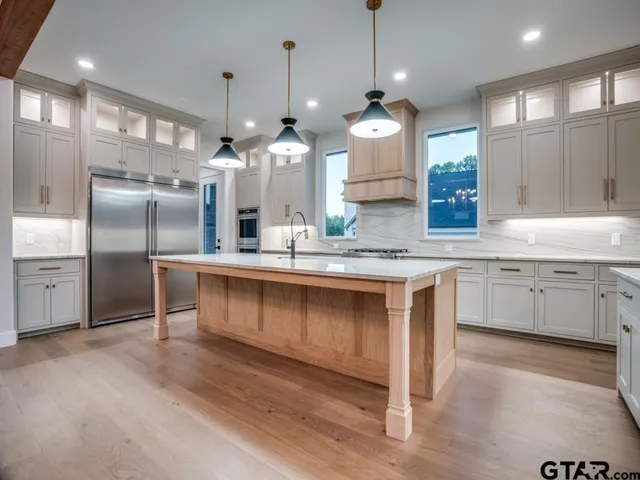 a kitchen with kitchen island granite countertop a sink cabinets and stainless steel appliances
