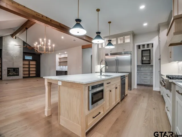 a large kitchen with stainless steel appliances a stove center island a wooden floor and chandelier
