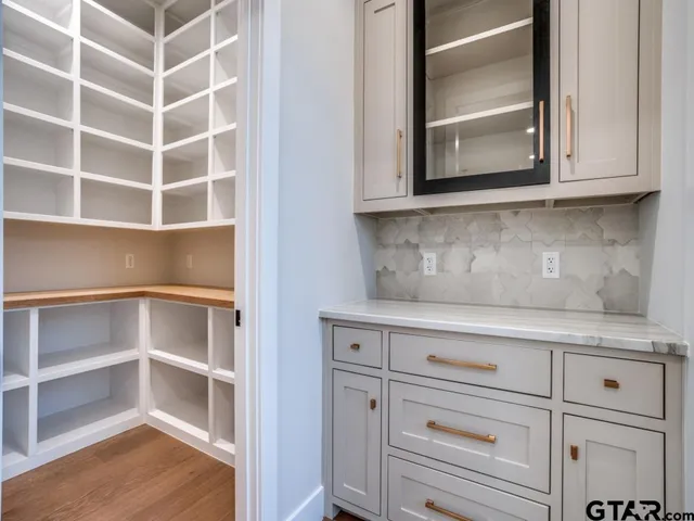 a view of an empty room with wooden floor and cabinets