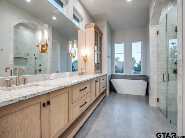 a spacious en suite bathroom with a granite countertop tub double vanity and a mirror