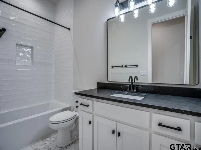 a bathroom with a granite countertop sink a toilet and bathtub
