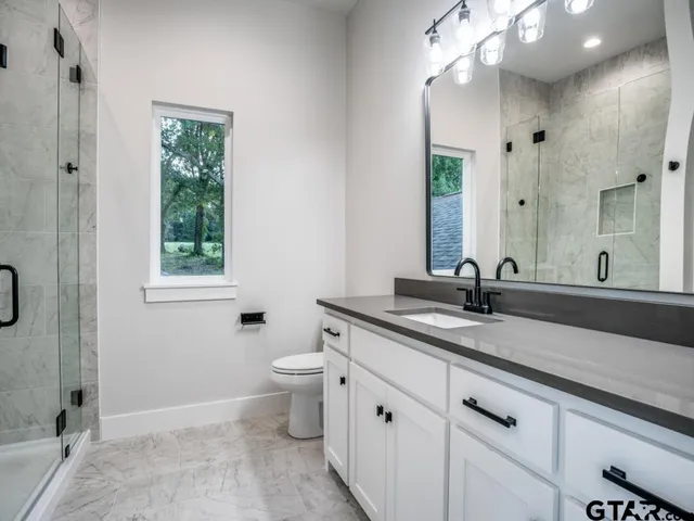 a bathroom with a granite countertop sink mirror and toilet