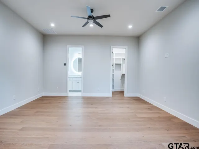 a view of empty room with wooden floor and ceiling fan