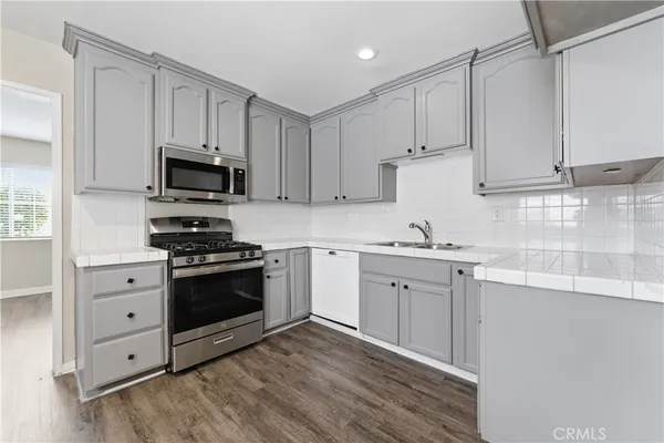 a kitchen with granite countertop a sink cabinets and stainless steel appliances