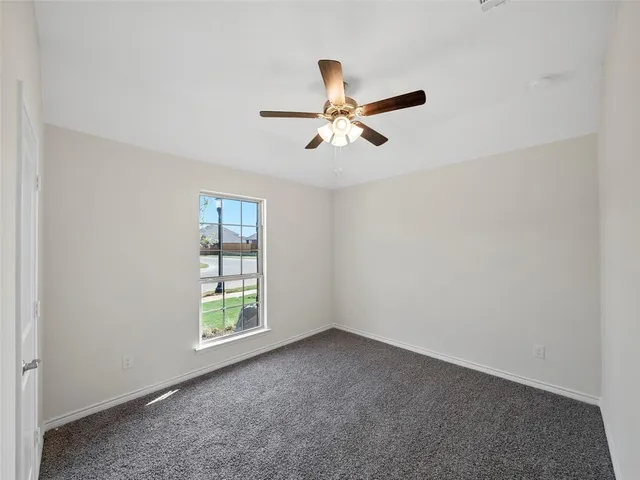 an empty room with ceiling fan and window
