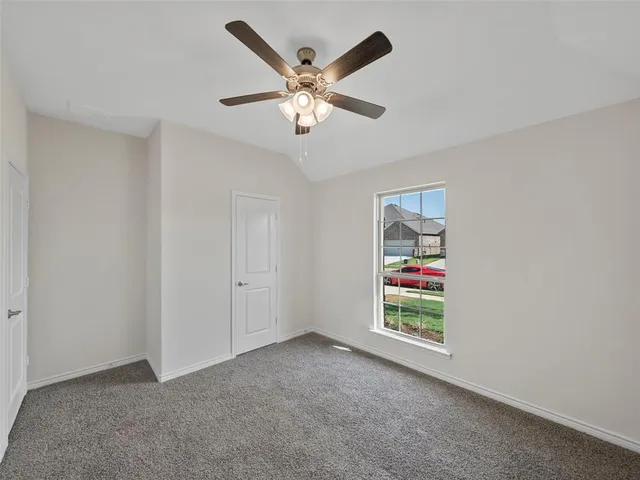 an empty room with ceiling fan and window