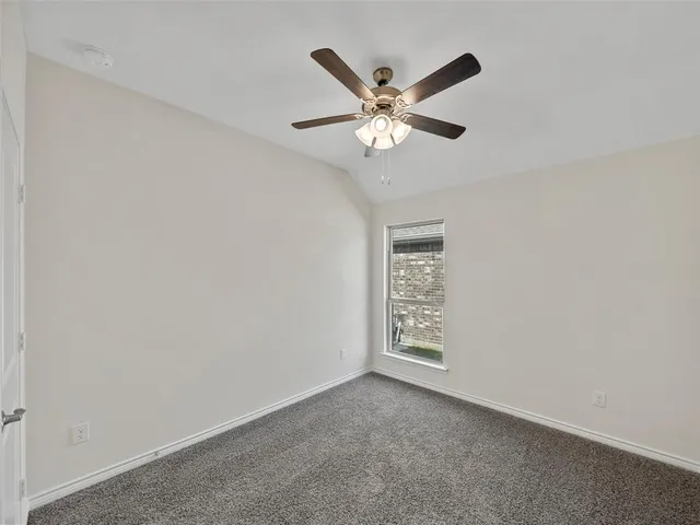 an empty room with a ceiling fan and a window