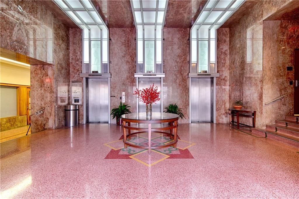 710 Colorado Street, Unit G9 Austin, TX 78701 - Photo 23 of 25 Elegant lobby showcasing multiple elevators, polished terrazzo flooring, and marble-clad walls.