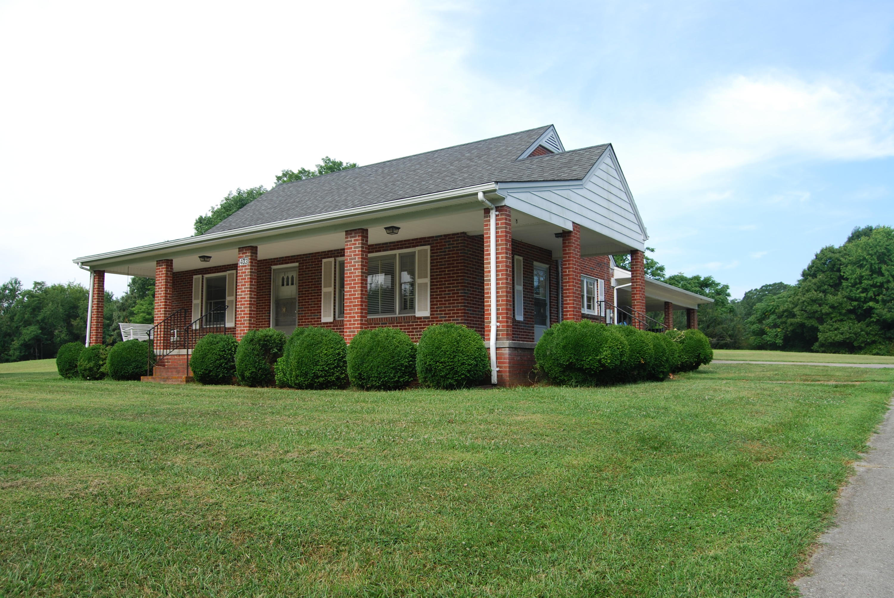 a view of a house next to a big yard and large trees
