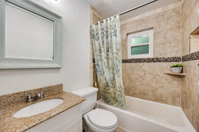 a bathroom with a granite countertop sink toilet a mirror and shower