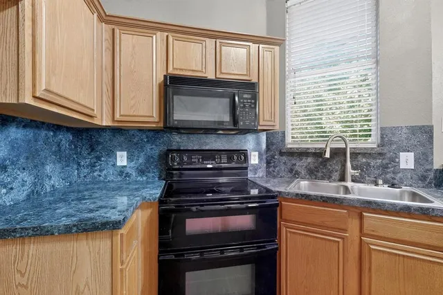 a kitchen with granite countertop a stove sink and cabinets