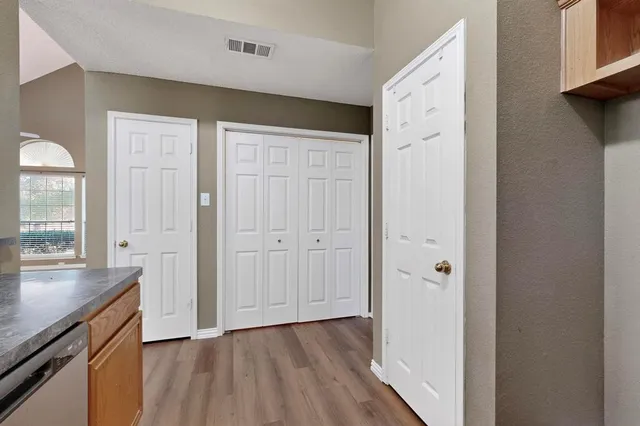 a view of a hallway with wooden floor and cabinet