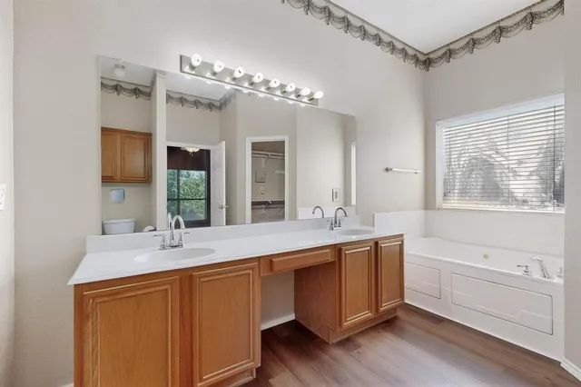 a bathroom with a double vanity sink a mirror a vanity and a bathtub