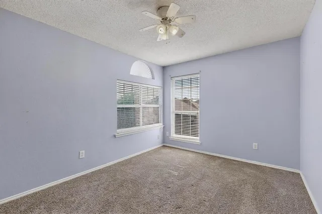 an empty room with chandelier fan and windows