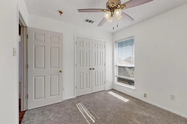 an empty room with windows and fan